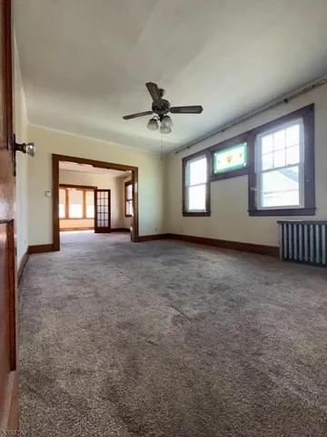an empty room with windows and ceiling fan