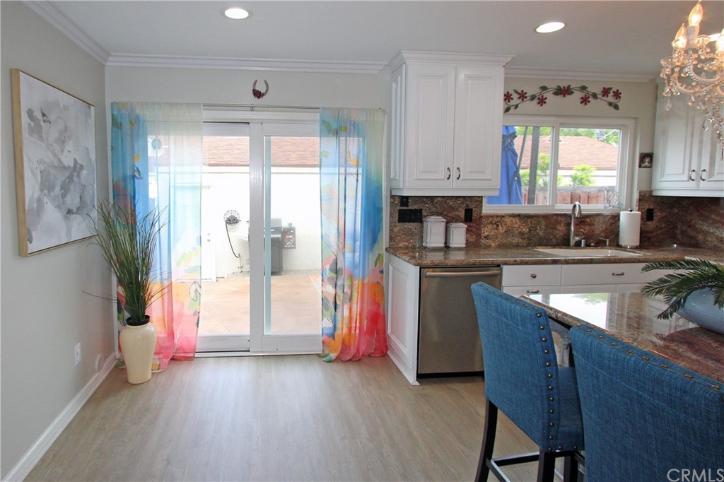 15030 Reedley Street, Unit C Moorpark, CA 93021 - Photo 2 of 23 a kitchen with stainless steel appliances granite countertop a refrigerator a sink dishwasher a stove and a dining table with wooden floor