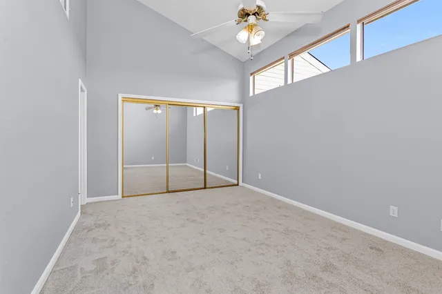 an empty room with chandelier fan and windows