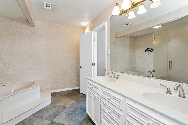 a bathroom with a double vanity sink a mirror and a bathtub