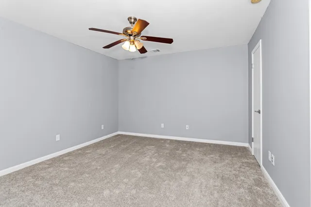 an empty room with a ceiling fan and window