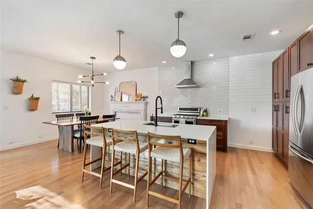 a kitchen with stainless steel appliances a dining table chairs stove refrigerator and cabinets