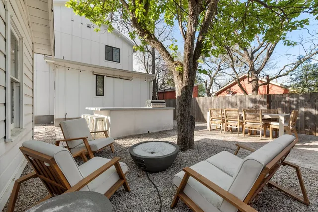 a view of a patio with couches table and chairs with wooden fence and large trees