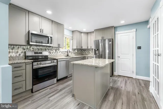 a kitchen with kitchen island granite countertop a sink stainless steel appliances and cabinets