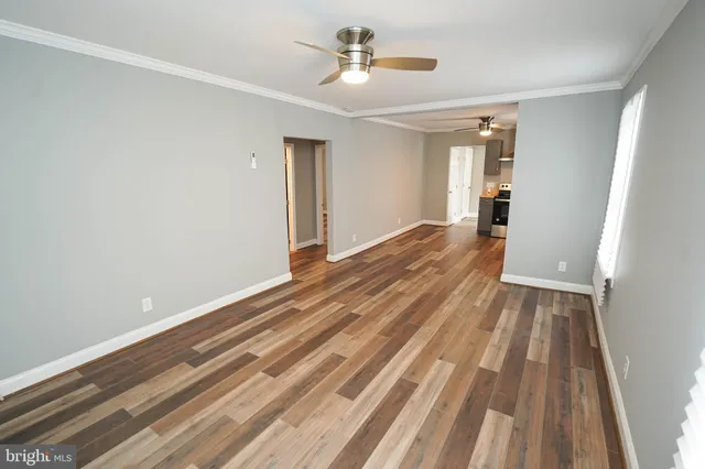 a view of a room with wooden floor ceiling fan and window