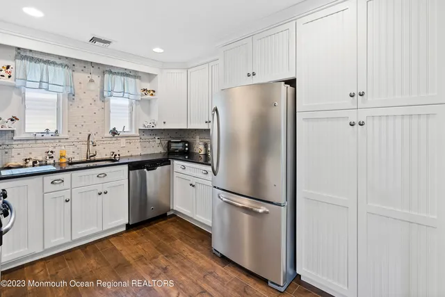 a kitchen with stainless steel appliances a stove a sink cabinets and wooden floor