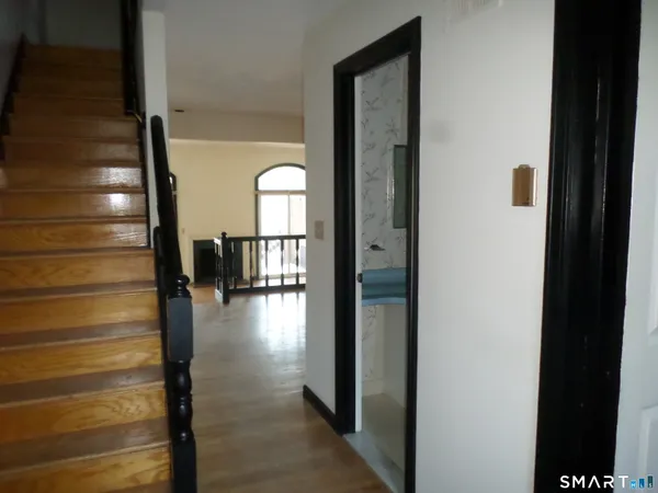 a view of a hallway with wooden floor and a bathroom