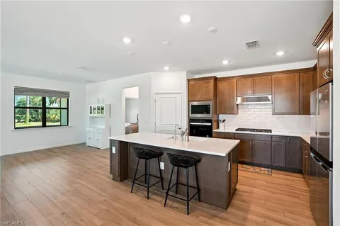 a kitchen with stainless steel appliances granite countertop wooden floor window and cabinets