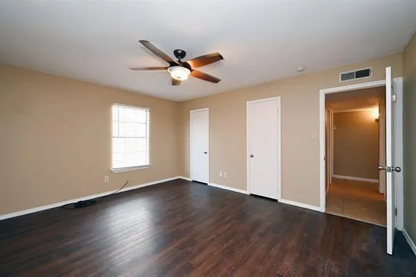 a view of empty room with wooden floor and fan