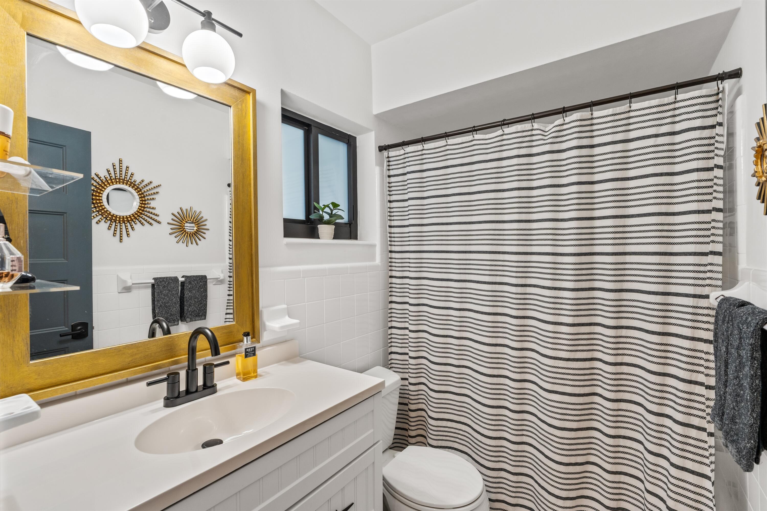 833 Northwest 6th Terrace Boca Raton, FL 33486 - Photo 22 of 49 a bathroom with a sink a toilet a mirror and shower curtain