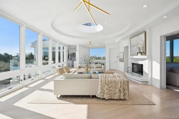 a living room with furniture large windows a rug and a chandelier