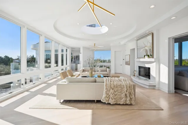 a living room with furniture large windows a rug and a chandelier