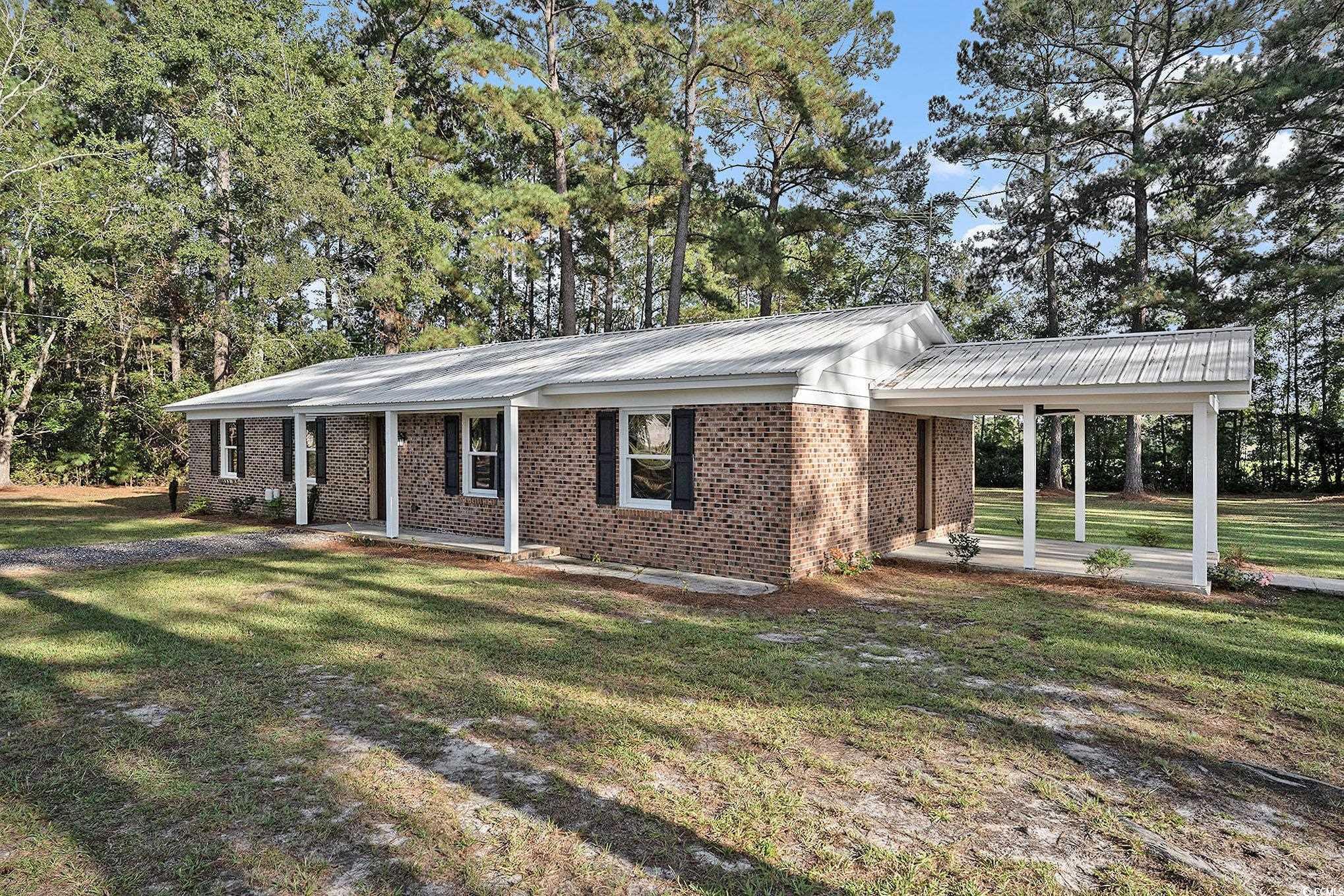 494 Ray Road Hemingway, SC 29554 - Photo 2 of 26 Ranch-style home with a front yard, a metal roof, brick siding, and view of scattered trees