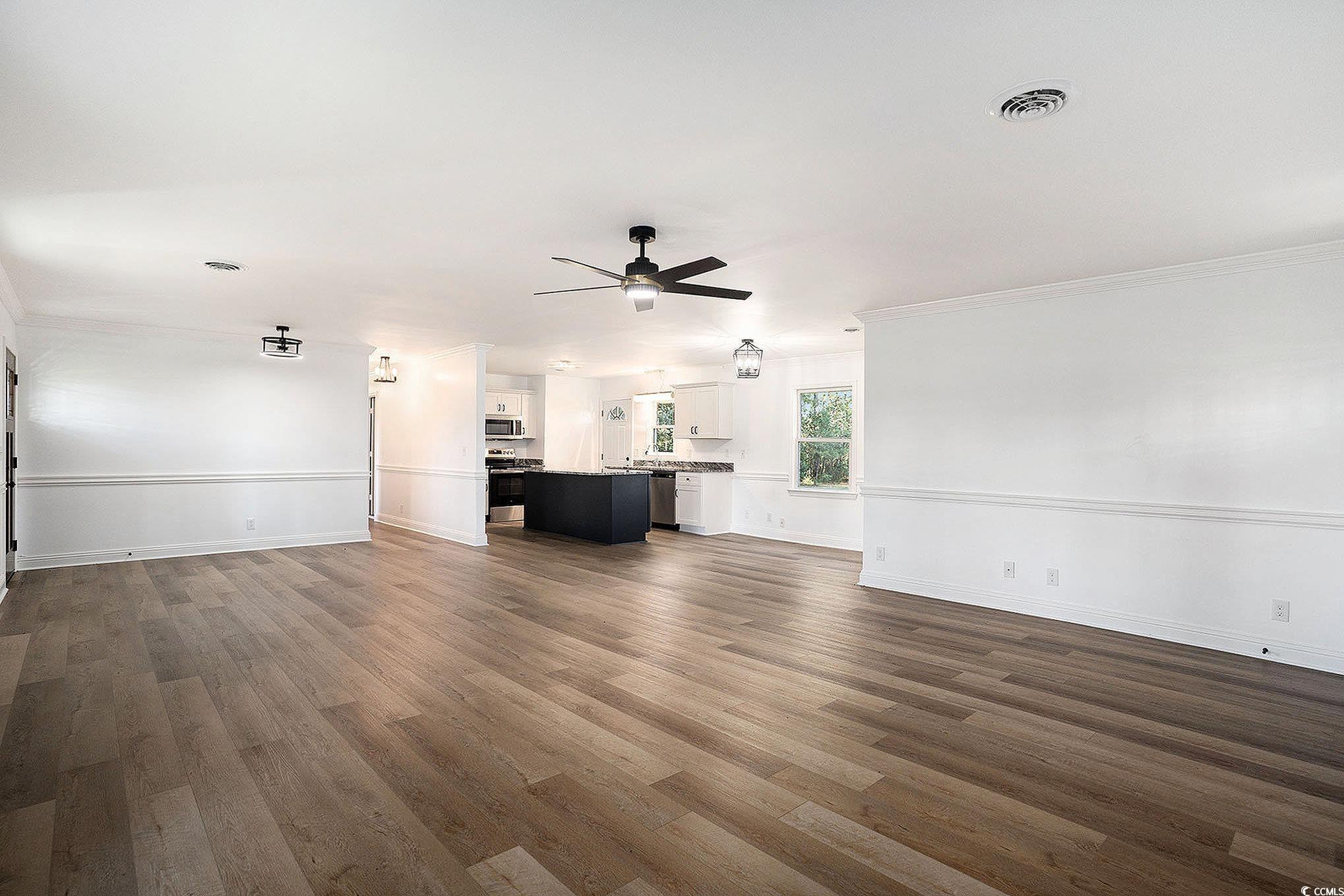 494 Ray Road Hemingway, SC 29554 - Photo 9 of 26 Unfurnished living room with dark wood-type flooring, crown molding, and ceiling fan