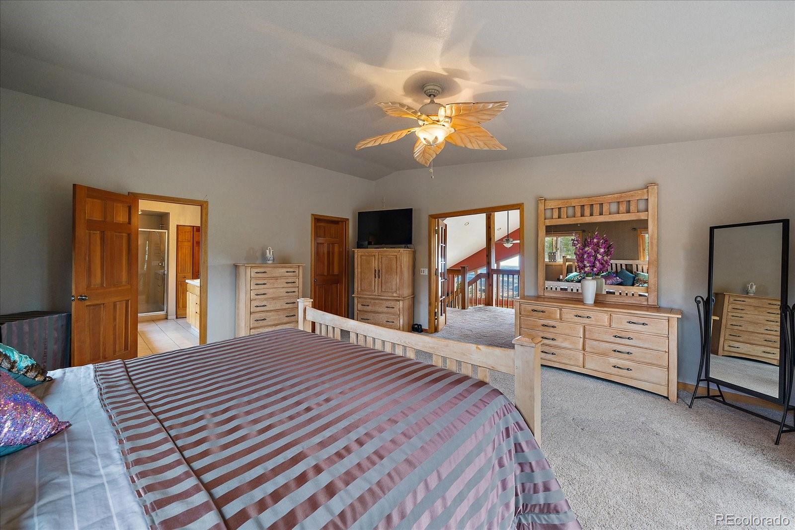 19791 Maxwell Drive Morrison, CO 80465 - Photo 31 of 50 a bedroom with a large bed and a chandelier