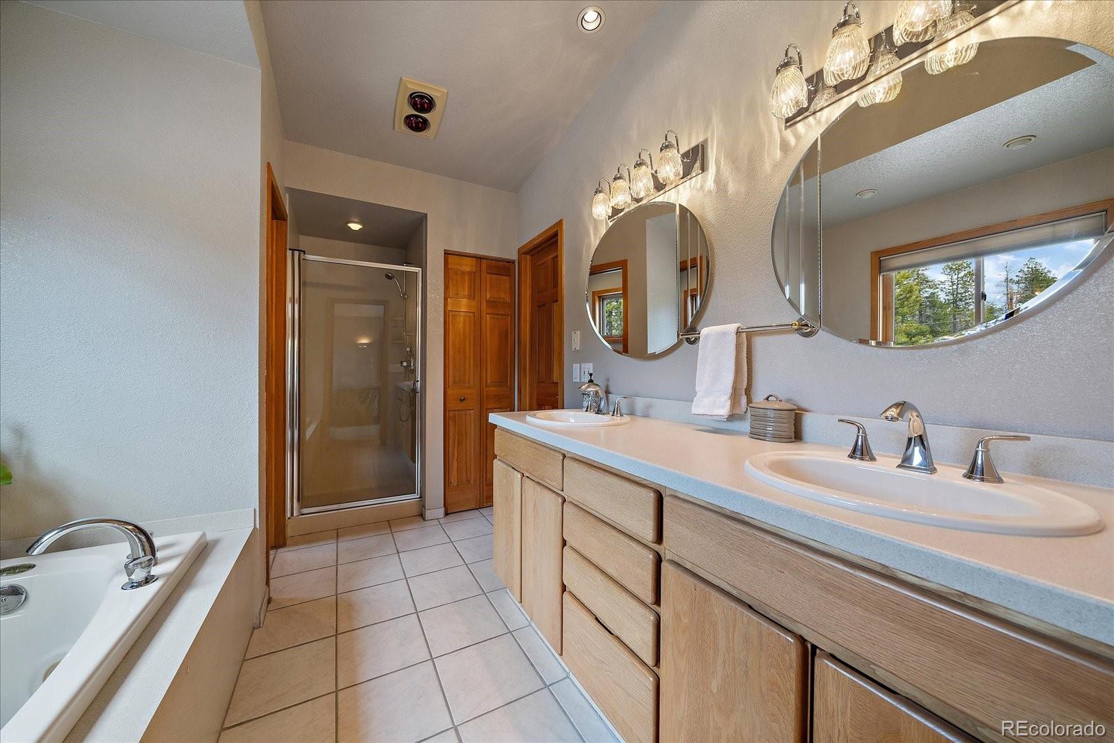19791 Maxwell Drive Morrison, CO 80465 - Photo 32 of 50 a bathroom with a double vanity sink a mirror and a shower