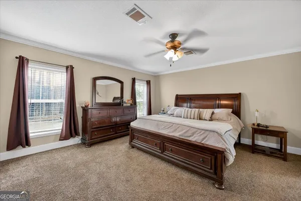 a spacious bedroom with a bed a dresser and a chandelier
