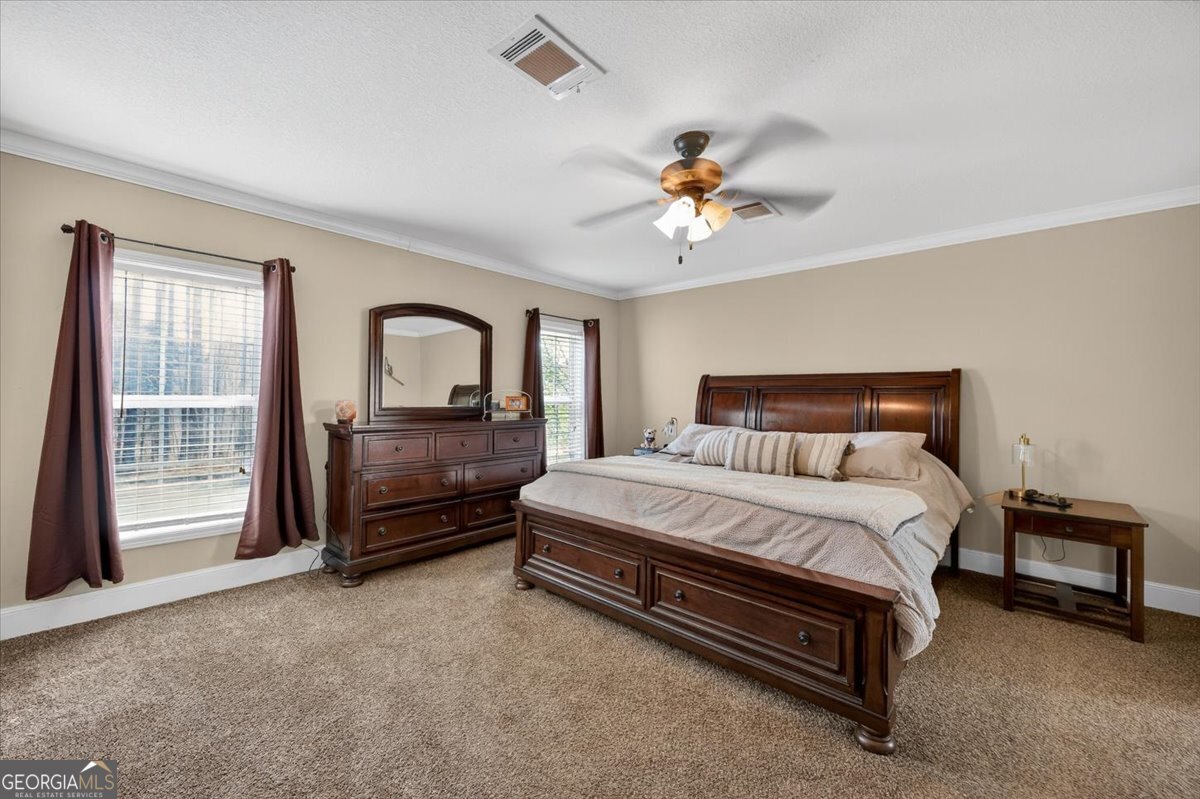550 Damascus Church Road Haddock, GA 31033 - Photo 12 of 34 a spacious bedroom with a bed a dresser and a chandelier