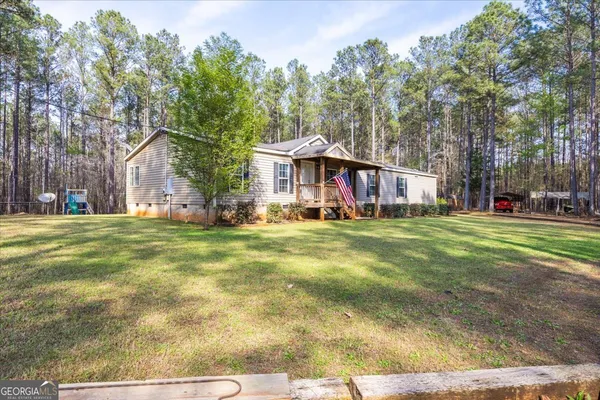 a view of a house with a big yard and large trees