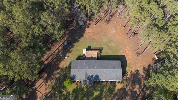 an aerial view of house with yard and trees all around