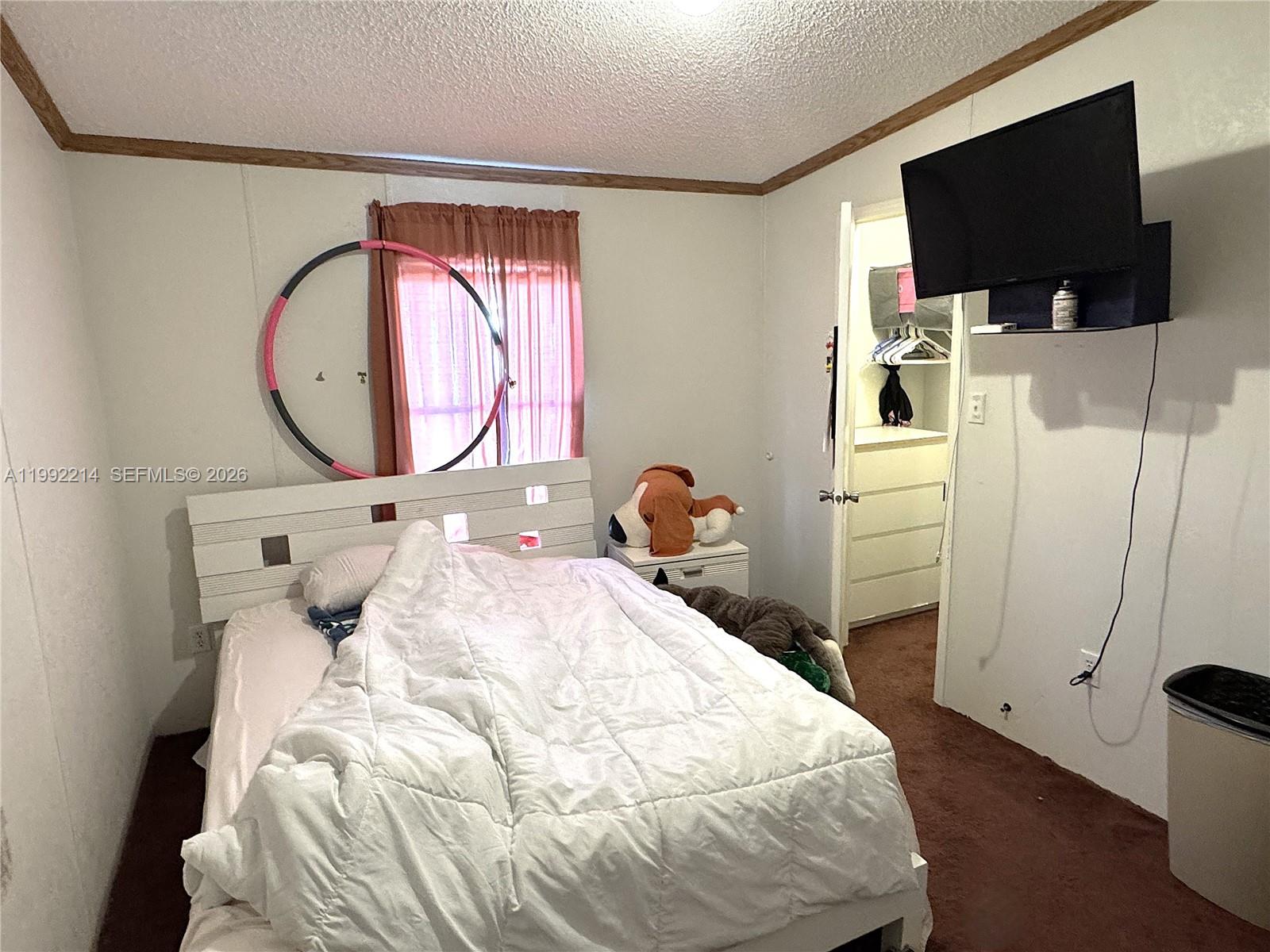 220 Northeast 12th Avenue, Unit 182 Homestead, FL 33030 - Photo 7 of 9 a bedroom with a bed and a flat tv screen on the dresser