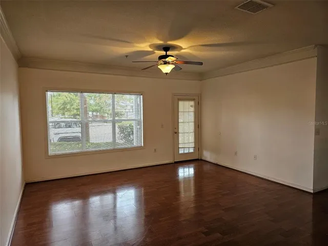 an empty room with wooden floor chandelier fan and windows