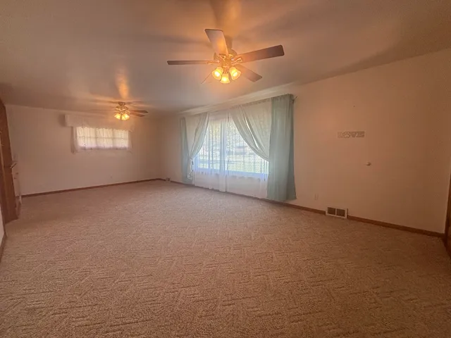 an empty room with a ceiling fan and window
