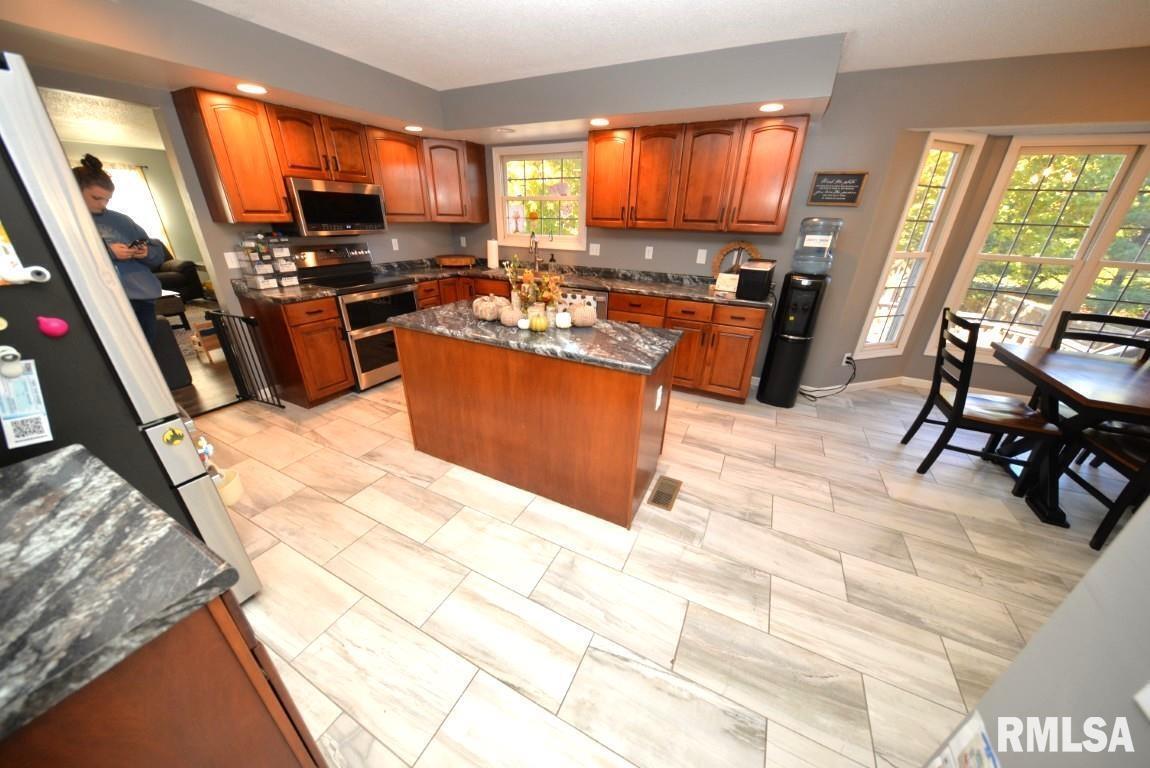 501 Cardinal Drive Mount Vernon, IL 62864 - Photo 28 of 57 a kitchen with stainless steel appliances kitchen island granite countertop a stove top oven a sink a dining table and chairs