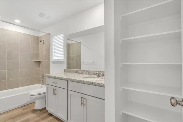 a bathroom with a granite countertop sink a toilet and bathtub