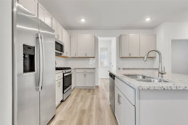a kitchen with kitchen island granite countertop a sink stove and refrigerator