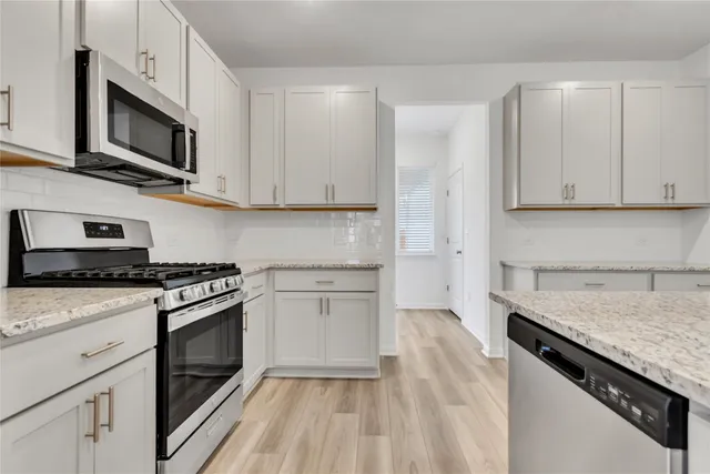 a kitchen with stainless steel appliances granite countertop a stove a sink and a microwave