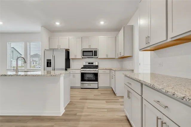 a kitchen with kitchen island white cabinets and stainless steel appliances