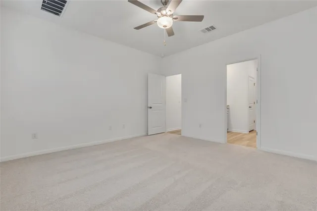 an empty room with closet and a ceiling fan