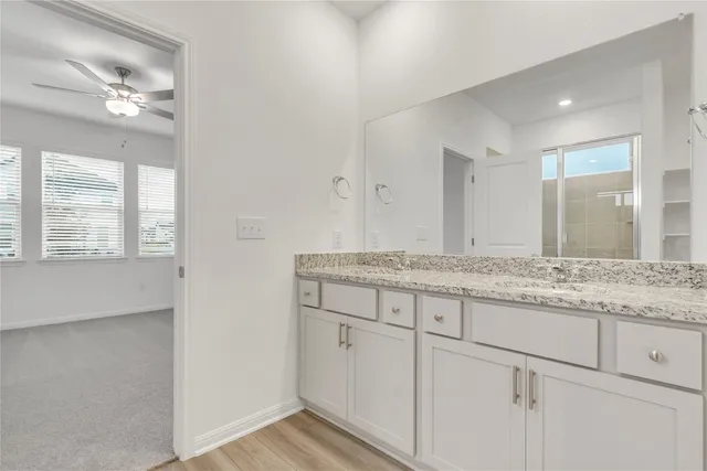 a bathroom with a granite countertop double vanity and mirror