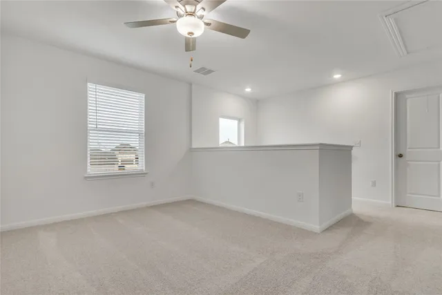 en empty room with windows and ceiling fan