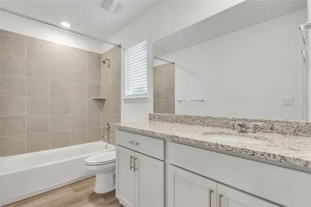 a bathroom with a granite countertop sink a toilet and bathtub