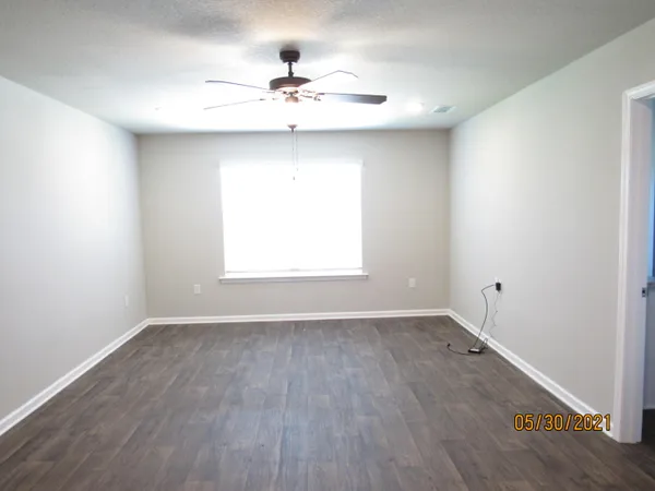 a view of an empty room with a window and wooden floor