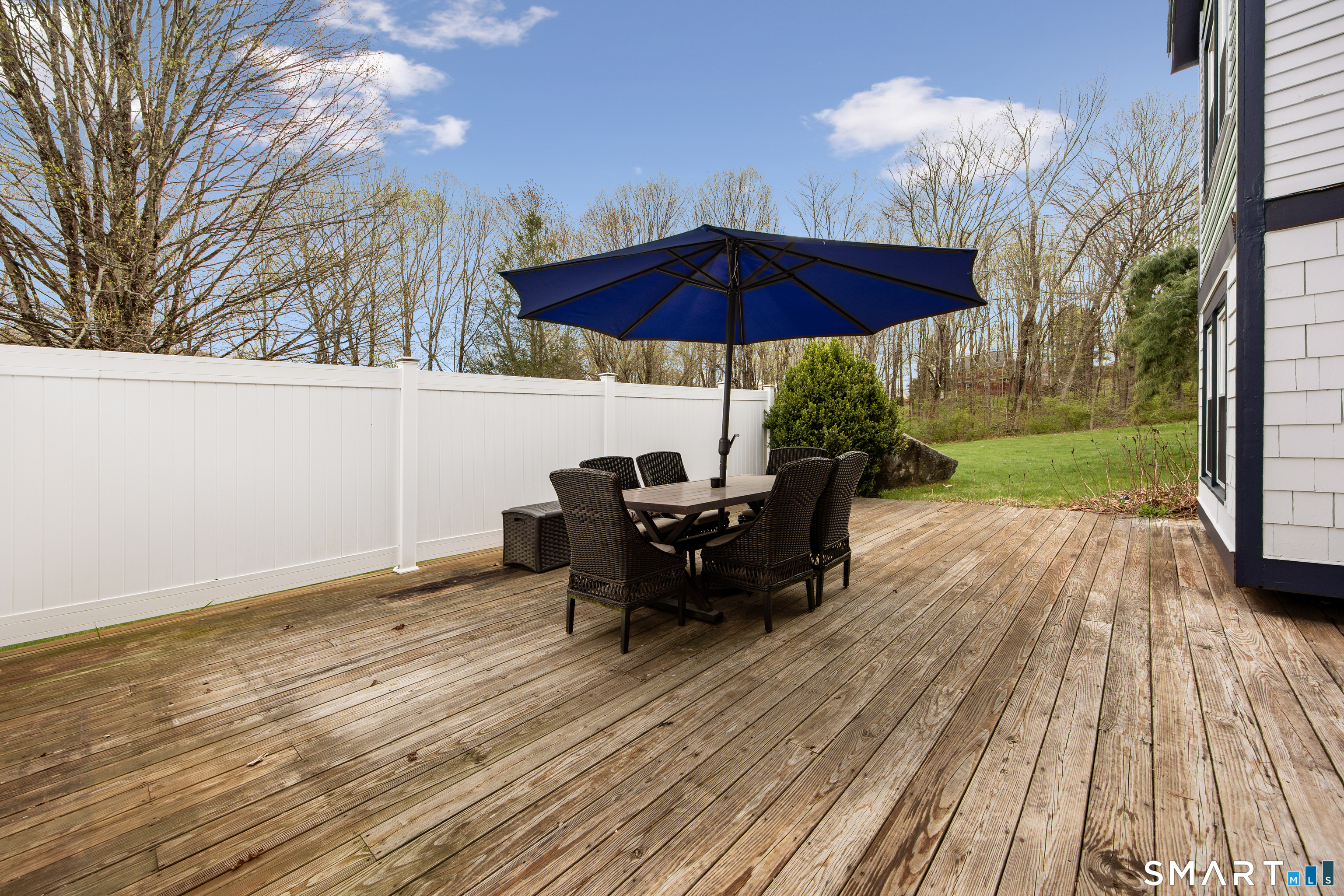 105 Quaker Farms Road Southbury, CT 06488 - Photo 35 of 40 a view of a deck with table and chairs under an umbrella with wooden floor and fence