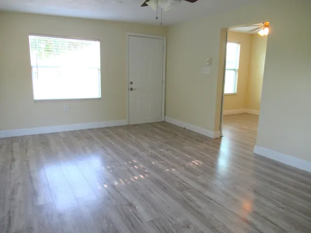 an empty room with wooden floor and windows