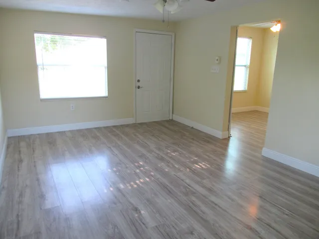 an empty room with wooden floor closet and windows