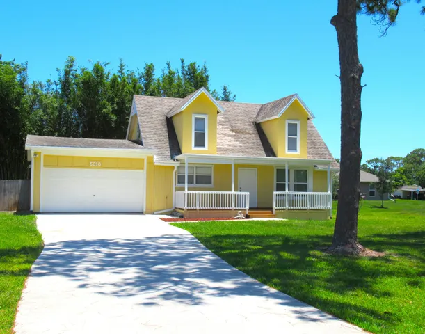 a view of a house with a yard and a tree