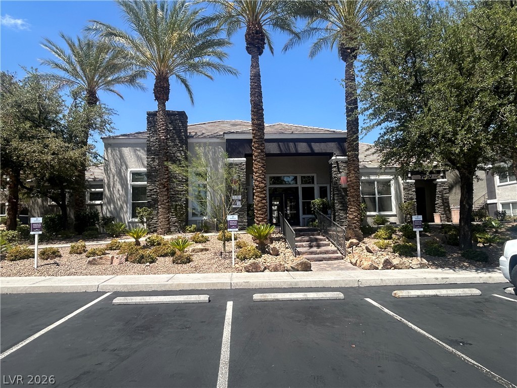 9620 West Russell Road, Unit 1010 Las Vegas, NV 89148 - Photo 8 of 9 Stone accents and lush desert landscaping adorn this inviting building entrance, complemented by mature palm trees.