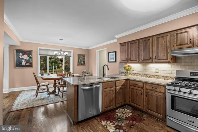 a kitchen with stainless steel appliances granite countertop a stove top oven a sink dishwasher and cabinets with wooden floor