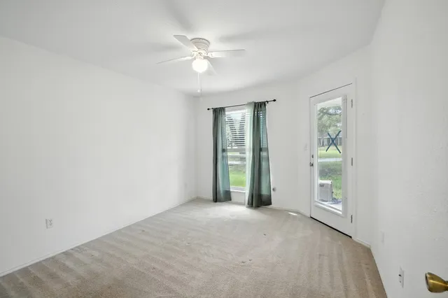 a view of an empty room with window and chandelier fan