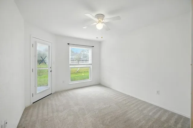 an empty room with a ceiling fan and a window