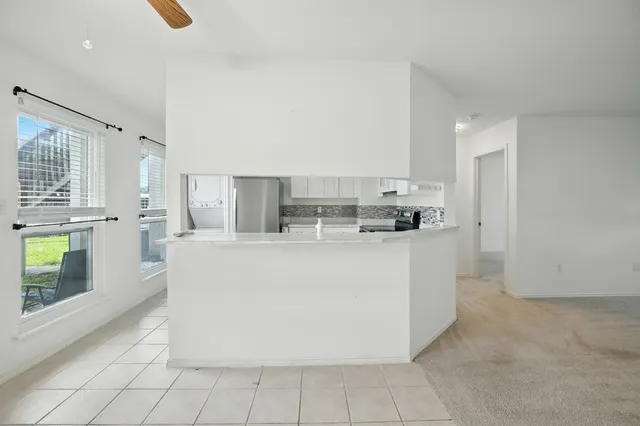 a view of kitchen with stainless steel appliances granite countertop a stove top oven a sink a refrigerator and white cabinets
