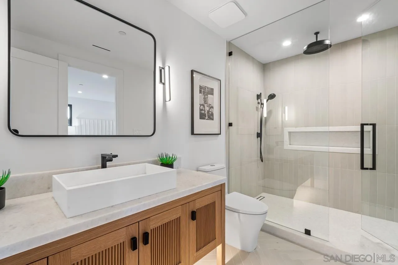 8433 Prestwick Drive La Jolla, CA 92037 - Photo 18 of 74 a bathroom with a granite countertop sink a toilet and a large mirror