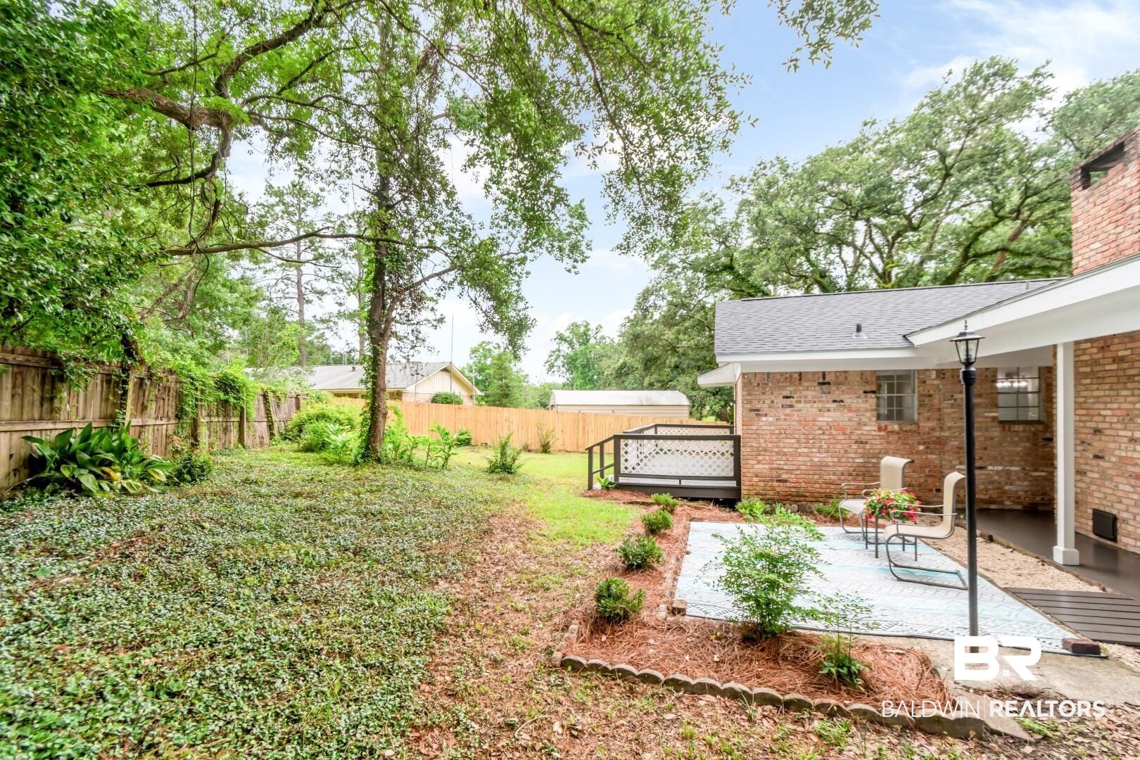 5217 Perin Road Mobile, AL 36693 - Photo 29 of 45 Expansive backyard featuring mature trees, a red brick exterior, a covered patio, a gravel patio, and a wooden fence