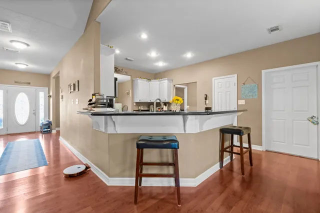 a kitchen with kitchen island stainless steel appliances a table chairs refrigerator sink and cabinets