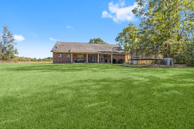 a view of a house with a big yard and large trees